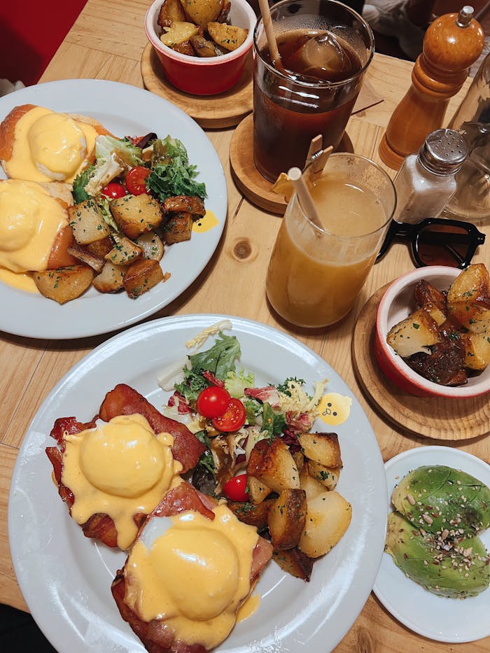 A tempting brunch spread featuring eggs benedict, roasted potatoes, and fresh juice.